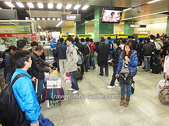 乘客在自助售票机排队买票。